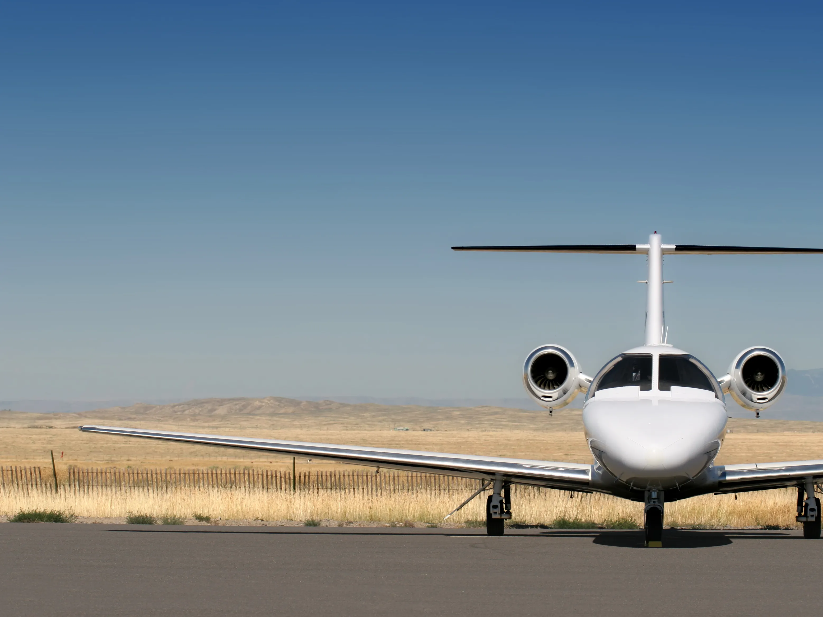 Business jet shown from its front standing against a plain field in the background