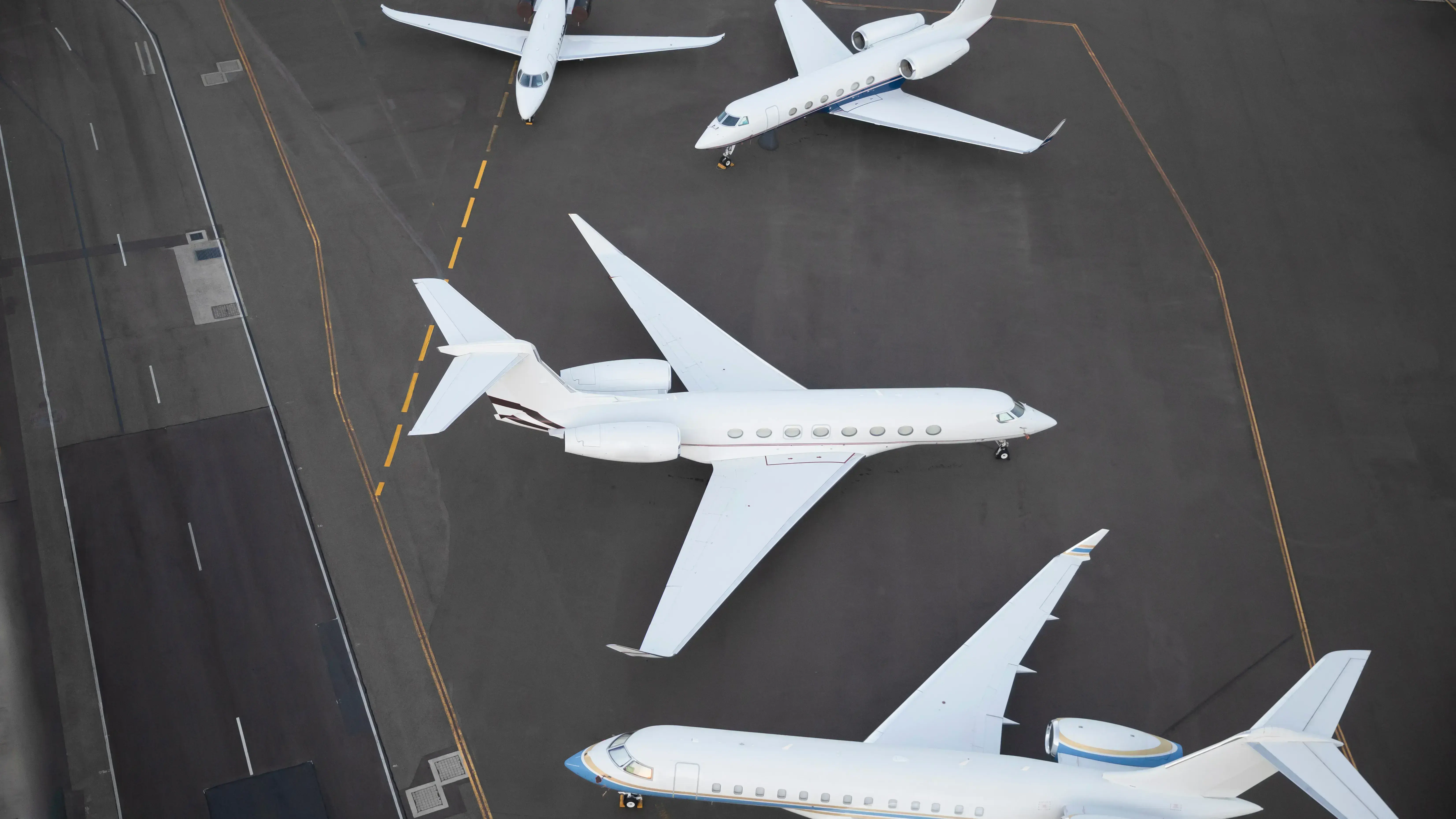 Several business jets standing beside a runway, facing different directions